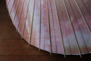 Parasol [de doble capa, teñido irregularmente, de color blanco rosado].