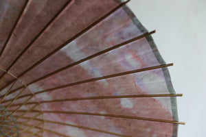 Parasol [de doble capa, teñido irregularmente, de color blanco rosado].